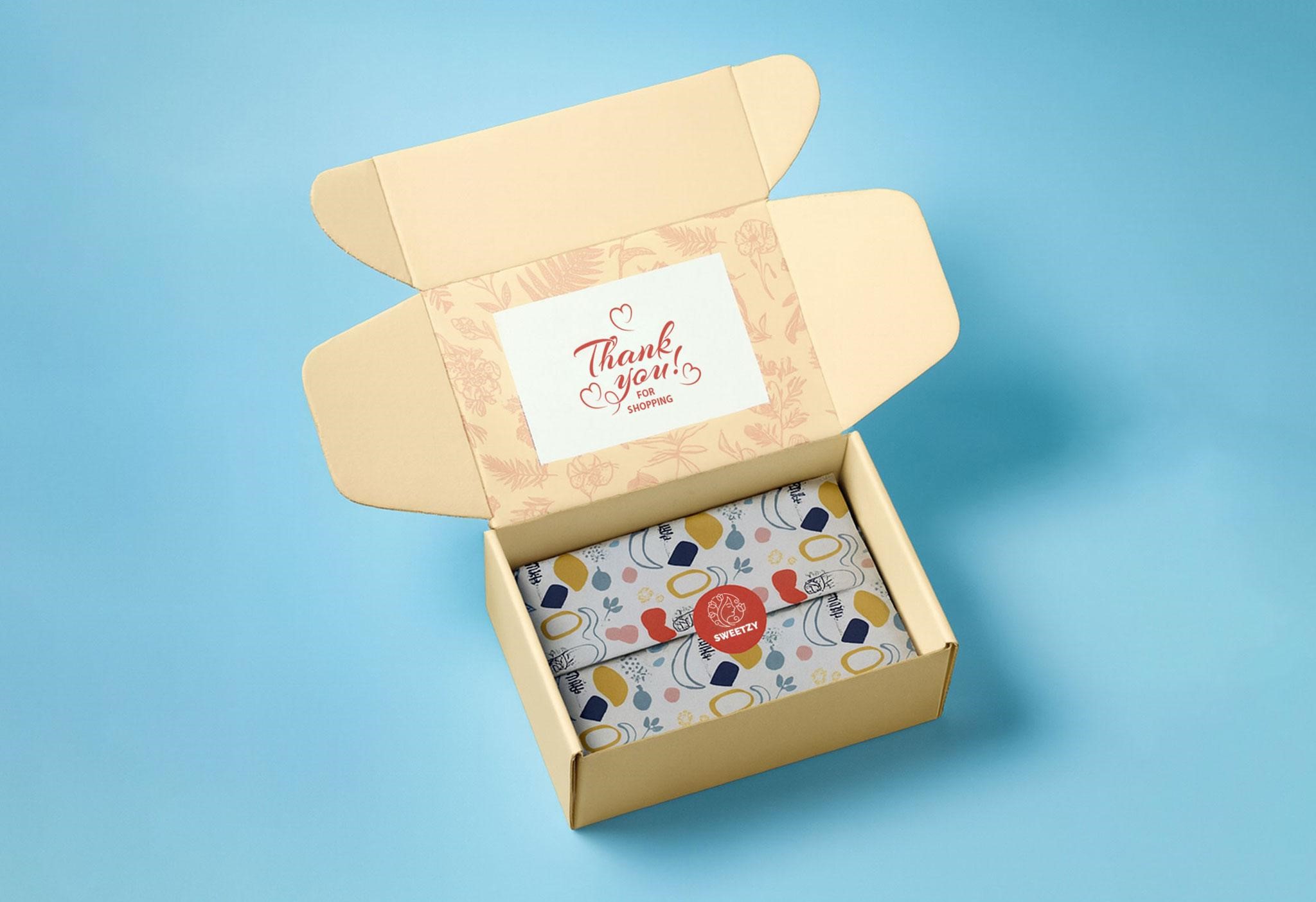 Custom e-commerce mailer box with branded tissue paper, sticker seal, and thank-you card for premium unboxing experience